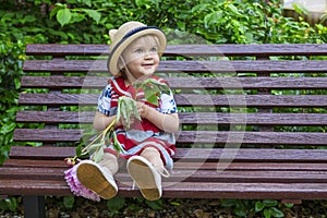 Cute toddler sitting on a bench with a flower