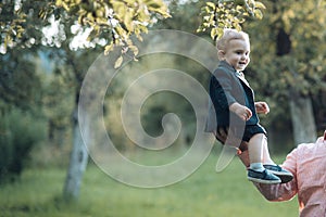 Cute toddler smile in suit, shirts, sneakers under tree, fashion