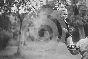 Cute toddler smile in suit, shirts, sneakers under tree, fashion