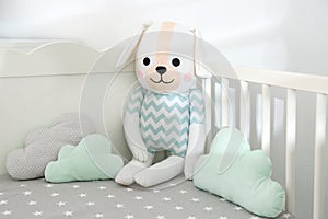 Cute toy dog and cloud shaped pillows in crib. Baby room interior elements