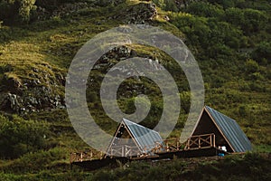 Cute triangle houses on a background of green grass of high mountains