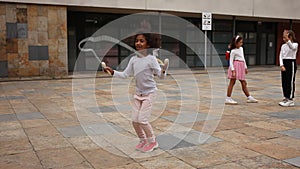 Cute tween African American girl skipping rope in schoolyard during break between lessons