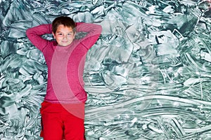 Cute tween boy relaxing on large green painting