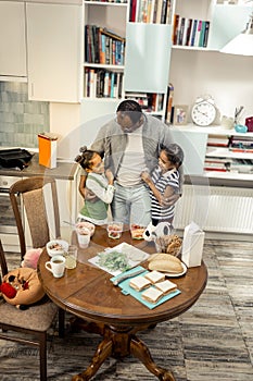 African-American father wearing jeans hugging his cute twins