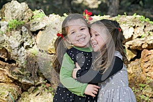 Cute twins girls are hugging each others at the nature background