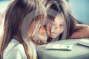 Cute twins little sisters using modern smarphone