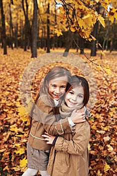 Cute two little sisters hugging in autumn park outdoor