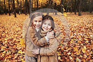Cute two little sisters hugging in autumn park outdoor