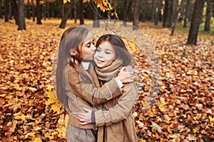 Cute two little sisters hugging in autumn park outdoor