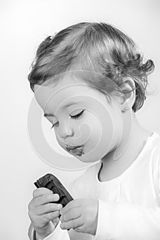 Cute two year old baby eating chocolate