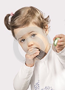 Cute two year old baby eating chocolate