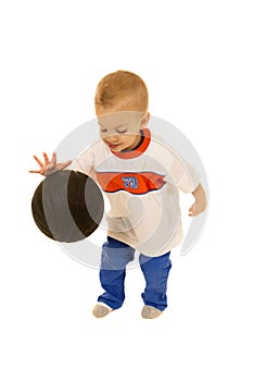 Cute two year old boy bouncing black basketball