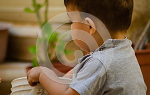 Cute two years old baby boy playing with dirt and plants