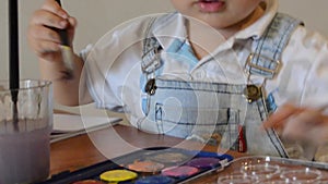 Cute two years old boy painting with water colours