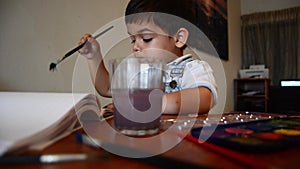 Cute two years old boy painting with water colours