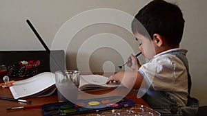 Cute two years old boy painting with water colours