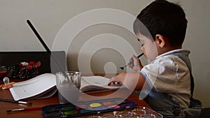 Cute two years old boy painting with water colours