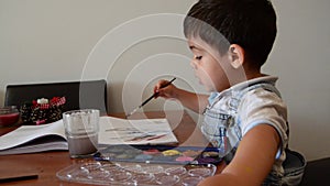 Cute two years old boy painting with water colours
