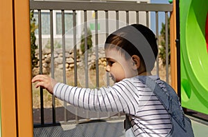 Cute two years old boy playig in the children playground outdoors on the playhouse