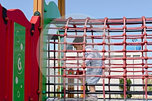 Cute two years old boy playig in the children playground outdoors on the playhouse