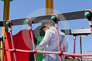 Cute two years old boy playig in the children playground outdoors on the playhouse