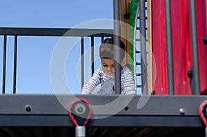 Cute two years old boy playig in the children playground outdoors on the playhouse