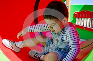 Cute two years old boy playig in the children playground outdoors in the tunnel