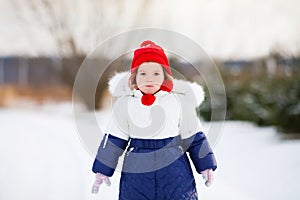 Little cute unhappy toddler girl outdoors on a sunny winter day.