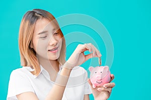 Cute university Asian teen girl happy saving money with smile piggy bank