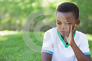 Cute upset boy thinking in the park