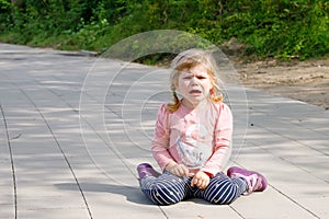 Cute upset unhappy toddler girl crying. Angry emotional child shouting. Portrait of kid with tears. Girl sitting on