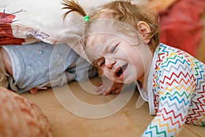 Cute upset unhappy toddler girl crying. Angry emotional child shouting. Portrait of kid with tears indoors