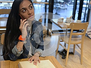 Cute urban girl sitting in cafe  reading  a book