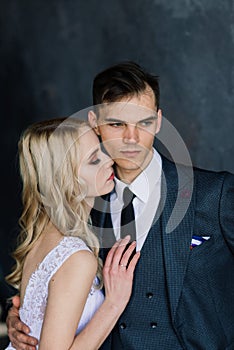 Cute wedding couple in the interior of a classic studio decorated. They kiss and hug each other