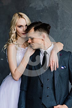 Cute wedding couple in the interior of a classic studio decorated. They kiss and hug each other