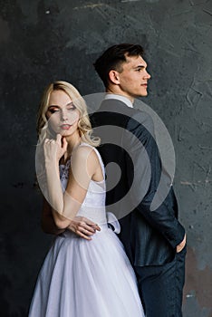 Cute wedding couple in the interior of a classic studio decorated. They kiss and hug each other