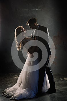 Cute wedding couple in the interior of a classic studio decorated. They kiss and hug each other