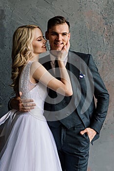 Cute wedding couple in the interior of a classic studio decorated. They kiss and hug each other