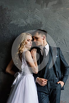 Cute wedding couple in the interior of a classic studio decorated. They kiss and hug each other