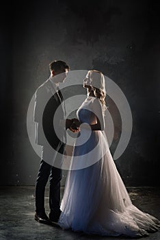 Cute wedding couple in the interior of a classic studio decorated. They kiss and hug each other