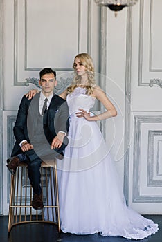 Cute wedding couple in the interior of a classic studio decorated. They kiss and hug each other