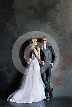 Cute wedding couple in the interior of a classic studio decorated. They kiss and hug each other