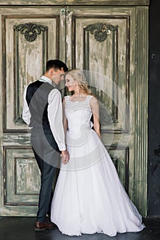 Cute wedding couple in the interior of a classic studio decorated. They kiss and hug each other