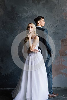 Cute wedding couple in the interior of a classic studio decorated. They kiss and hug each other