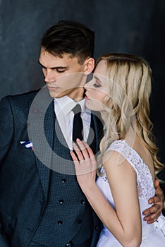 Cute wedding couple in the interior of a classic studio decorated. They kiss and hug each other.