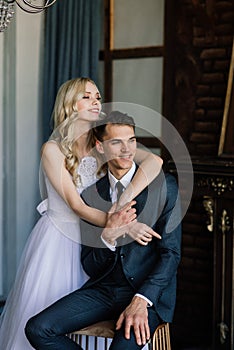 Cute wedding couple in the interior of a classic studio decorated. They kiss and hug each other.