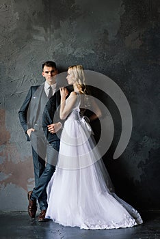 Cute wedding couple in the interior of a classic studio decorated. They kiss and hug each other.