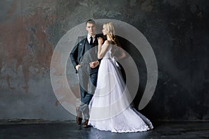 Cute wedding couple in the interior of a classic studio decorated. They kiss and hug each other.