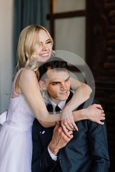 Cute wedding couple in the interior of a classic studio decorated. They kiss and hug each other.