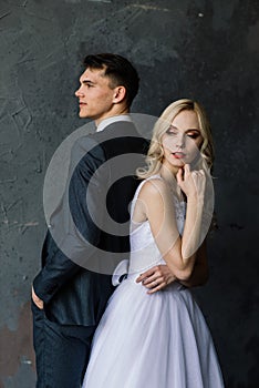 Cute wedding couple in the interior of a classic studio decorated. They kiss and hug each other.